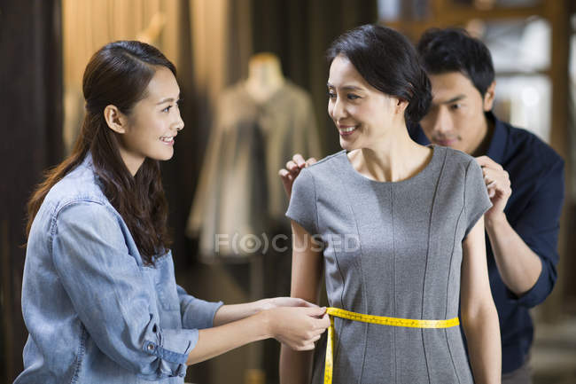 Chinese fashion designers taking measurement of customer — Stock Photo