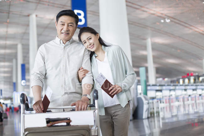 Зрелая китайская пара, стоящая в аэропорту с билетами — стоковое фото