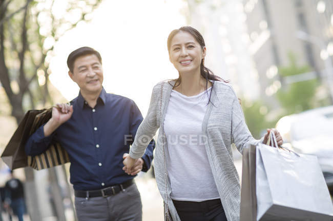 Mature chinese couple with shopping bags in city — Stock Photo