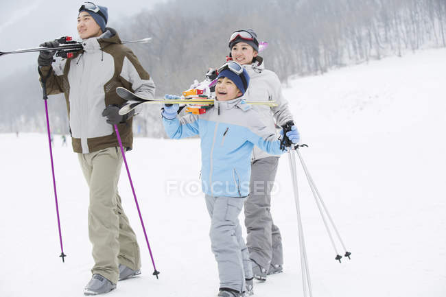 Chinese parents with son walking with skis on shoulders in ski resort — Stock Photo