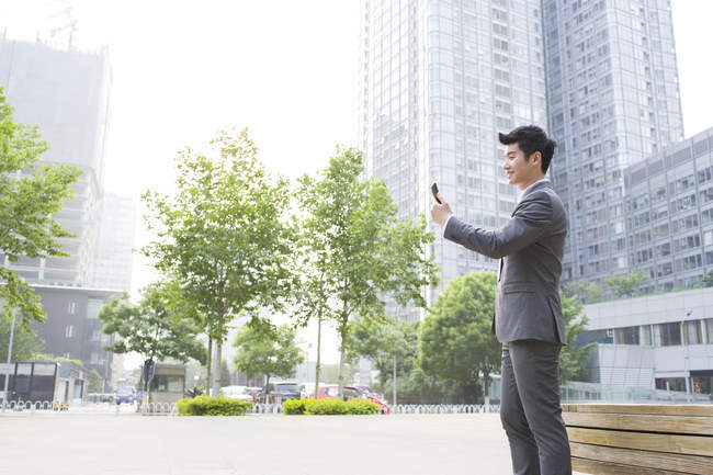 Китайский бизнесмен использует смартфон на улице — стоковое фото