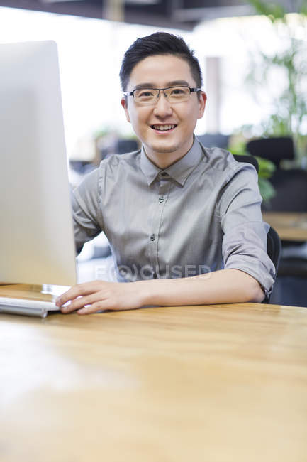 Trabajador de oficina chino usando computadora en la oficina - foto de stock