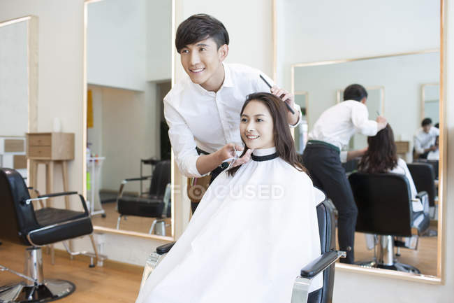 Chinese barber with female customer looking in mirror — Stock Photo