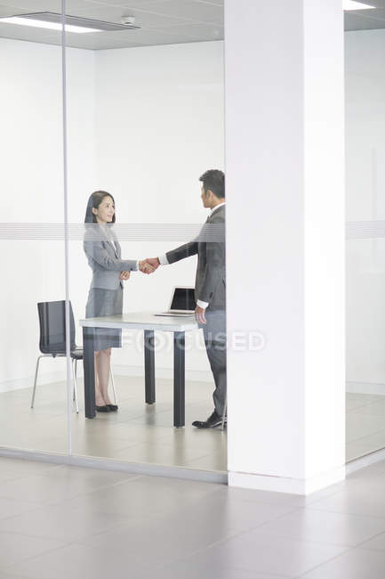 Chinese business people shaking hands in meeting room — Stock Photo