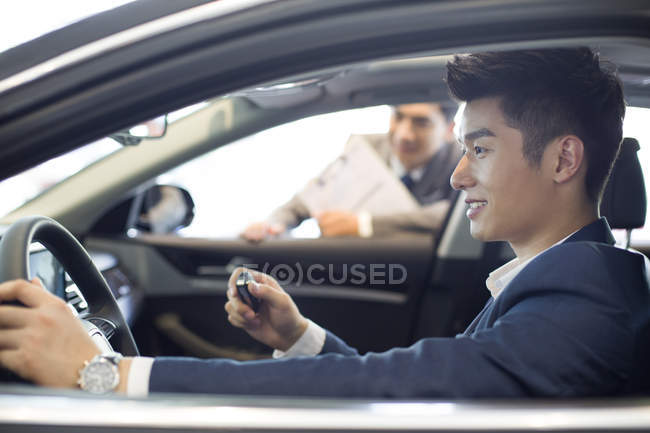 Homem chinês sentado no carro enquanto test drive — Fotografia de Stock
