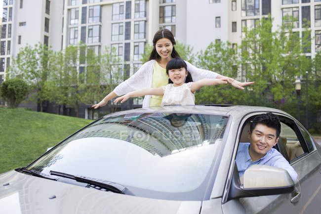 Chinese family leaning out of car and smiling — Stock Photo