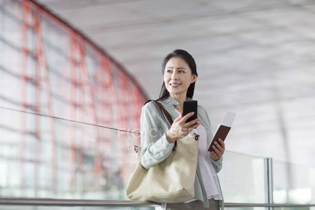 Donna cinese con smartphone e biglietto all'aeroporto — Foto stock