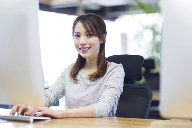 Mujer china trabajando con computadora en la oficina - foto de stock