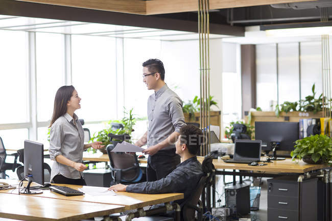 Chinese co-workers talking in office — Stock Photo