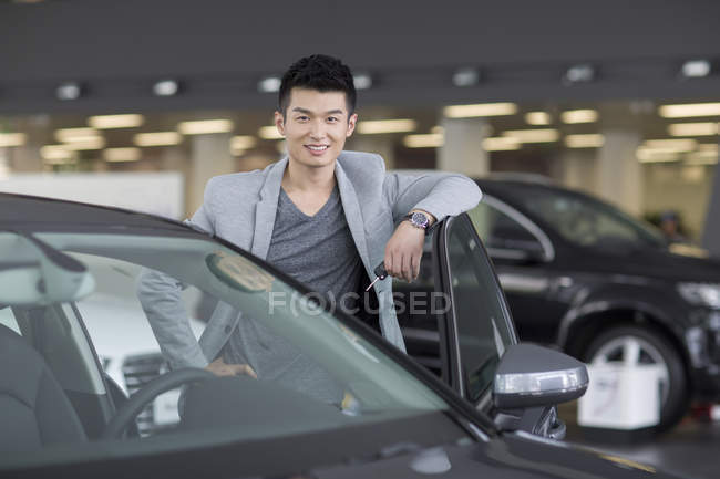 Chinese posiert mit Auto auf Parkplatz — Stockfoto