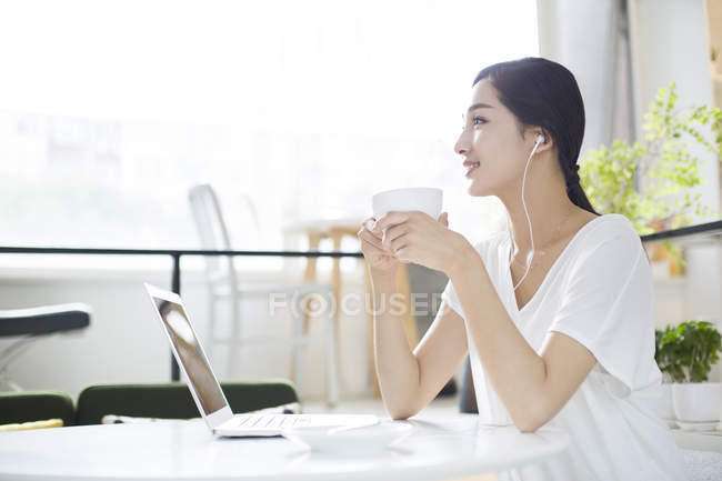 Mujer china escuchando música en la cafetería - foto de stock