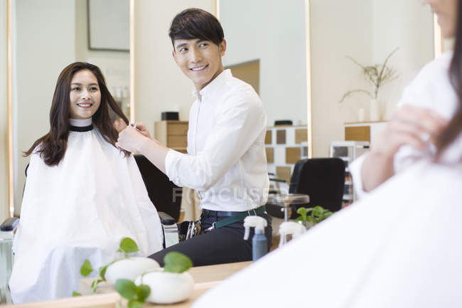 Chinese barber with female customer looking in mirror — Stock Photo
