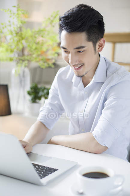 Uomo cinese che utilizza il computer portatile in caffetteria — Foto stock