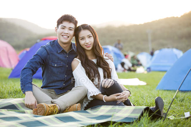 Abbracciare coppia seduta sul prato del festival — Foto stock