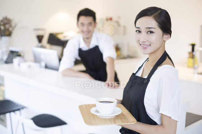 Chinese coffee shop waitress standing with cup of coffee — Stock Photo