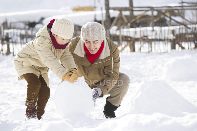 Китайский отец и сын катают снежок вместе — стоковое фото