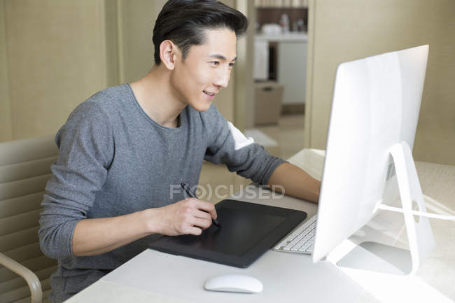 Chinese male illustrator making sketch on drawing tablet — Stock Photo