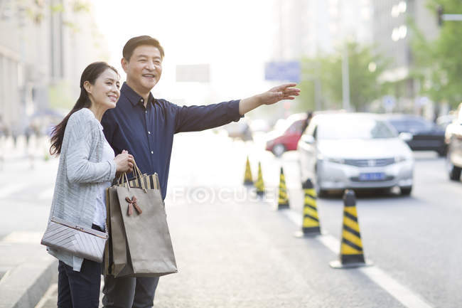 Зрелая китайская пара жестикулирует на улице с сумками для покупок — стоковое фото
