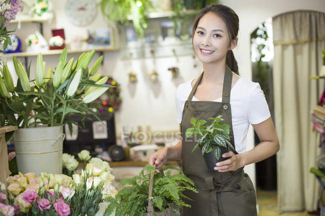 Chinese shopkeeper holding plants in florist store — Stock Photo