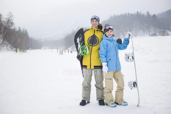 Chinese couple of snowboarders standing on slope — Stock Photo