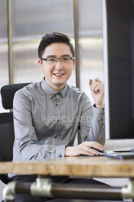 Travailleur informatique chinois assis sur le lieu de travail — Photo de stock