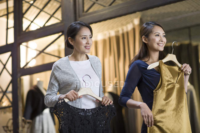 Mature Chinese boutique owner helping customer choosing dress — Stock Photo