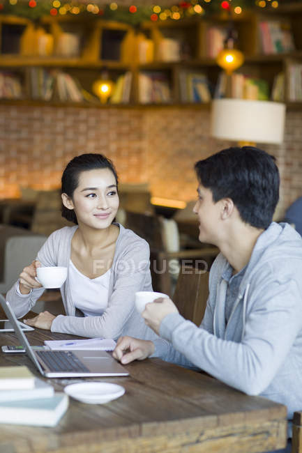 Étudiants chinois avec ordinateur portable et café dans un café — Photo de stock
