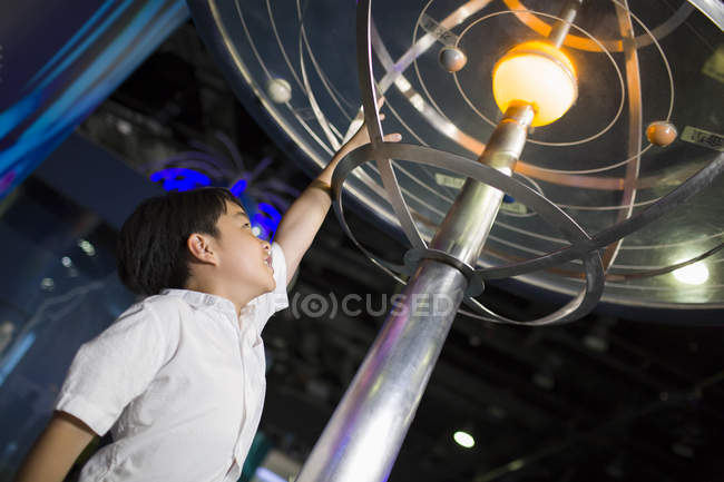 Chico chino mirando la exposición del sistema solar en el museo - foto de stock