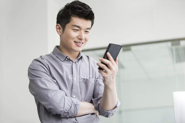 Chinesischer Geschäftsmann mit Smartphone im Büro — Stockfoto