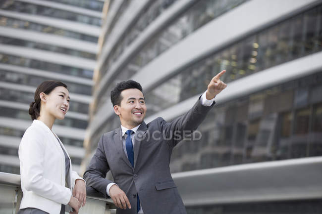 Empresário chinês na rua com mulher apontando e olhando para a vista — Fotografia de Stock