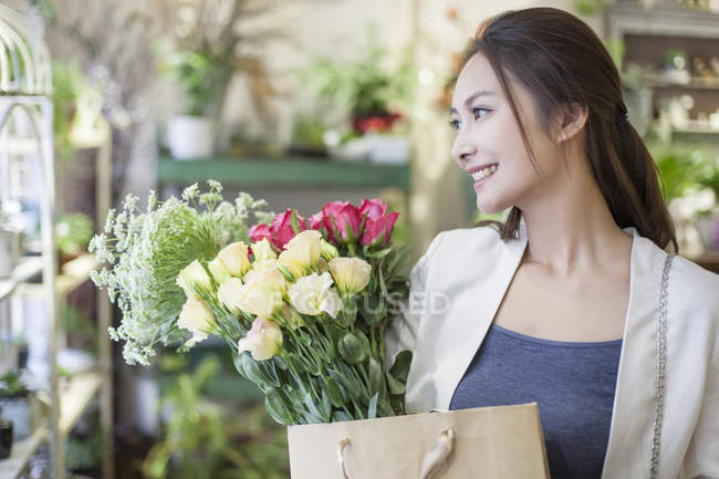Donna cinese in piedi con mazzi di fiori in negozio — Foto stock