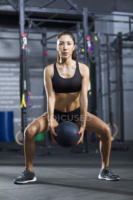 Китайська жінка, що тренування з м'ячем медицини в тренажерний зал — стокове фото
