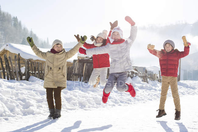 Niños chinos saltando en la nieve - foto de stock