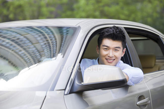 Homem chinês sentado no carro e olhando na câmera — Fotografia de Stock