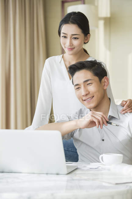 Jeune couple chinois utilisant un ordinateur portable à la maison — Photo de stock
