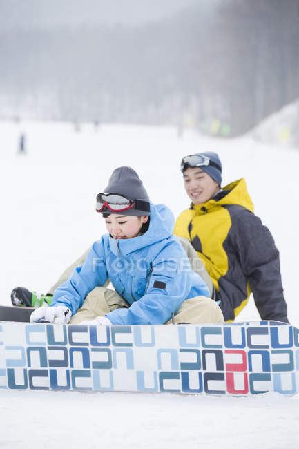 Pareja china usando tablas de snowboard en la nieve - foto de stock