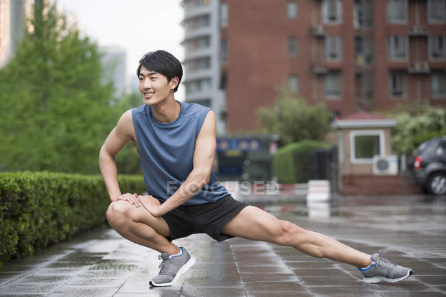 Chinese man stretching legs on street — Stock Photo