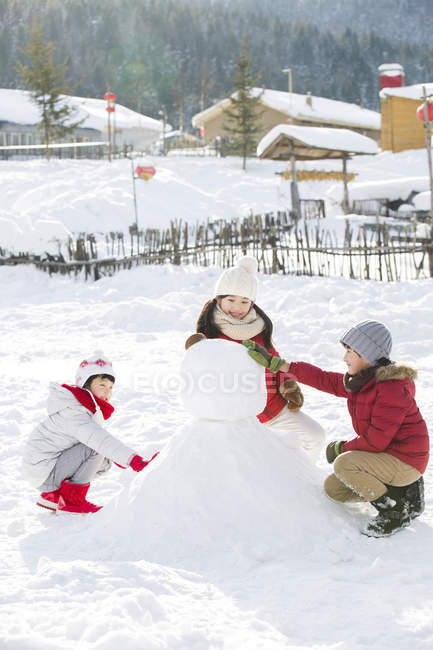 Niños chinos haciendo muñeco de nieve al aire libre - foto de stock