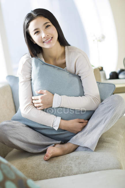 Китаянка обнимает подушку на домашнем интерьере — стоковое фото