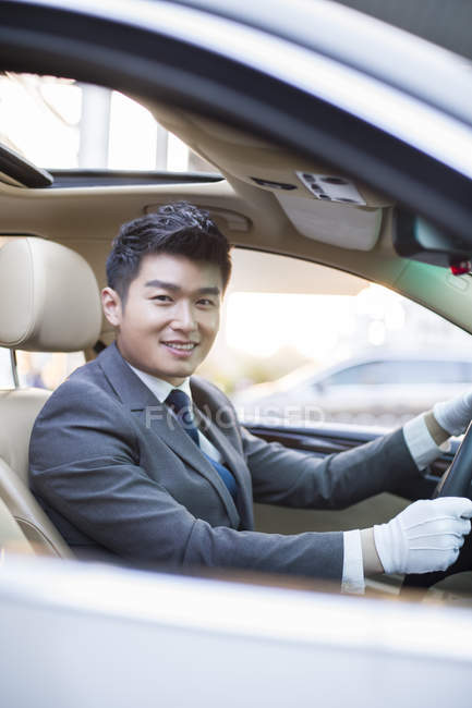 Chófer chino conduciendo coche y mirando en la cámara - foto de stock
