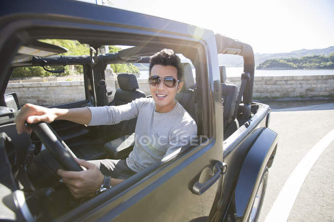 Homem chinês dirigindo carro e olhando na câmera — Fotografia de Stock