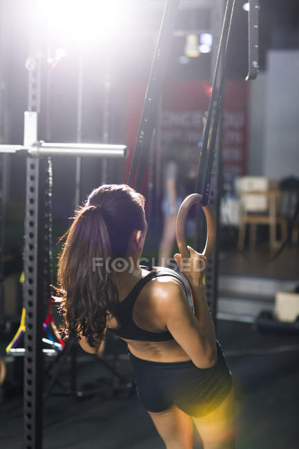 Mulher se exercitando com anéis de ginástica no ginásio — Fotografia de Stock