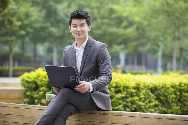 Chinesischer Geschäftsmann arbeitet mit Laptop auf Straßenbank — Stockfoto