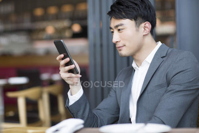Китаєць за допомогою смартфона в ресторані — стокове фото
