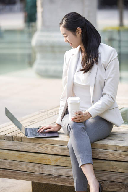Femme d'affaires chinoise travaillant avec ordinateur portable et café — Photo de stock