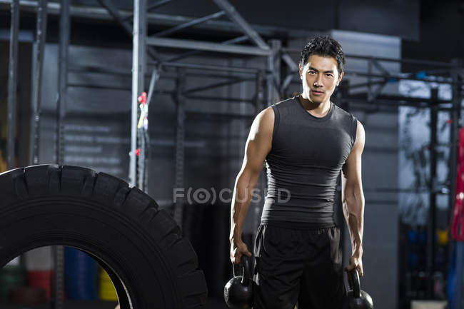 Chinesischer Mann trainiert mit Kettlebells in Crossfit-Fitnessstudio — Stockfoto