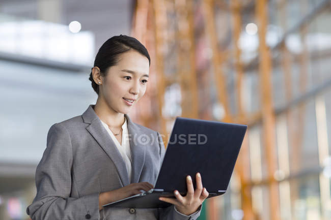 Empresaria china usando portátil en el interior - foto de stock