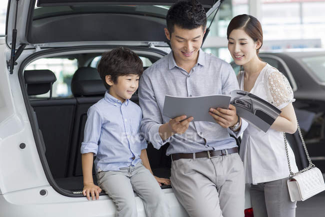 Chinese family looking into car catalog in showroom — Stock Photo