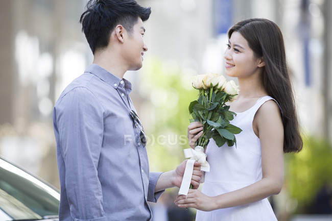 Chinese man giving flowers to girlfriend — Stock Photo