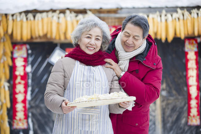 Старшая пара держит блюдо из традиционных пельменей — стоковое фото